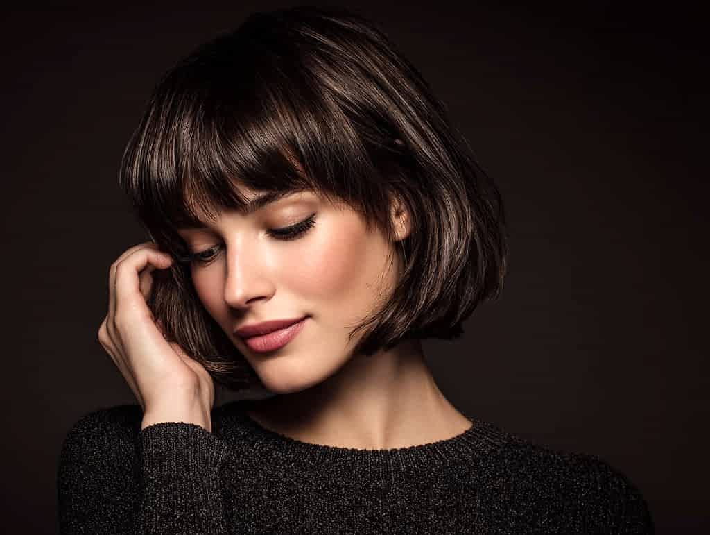 Woman with stylish fringe touching hair, professional bangs haircut